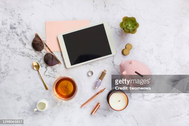 flat lay marble women's dressing table top with digital tablet and piggy bank. - candle overhead stock-fotos und bilder