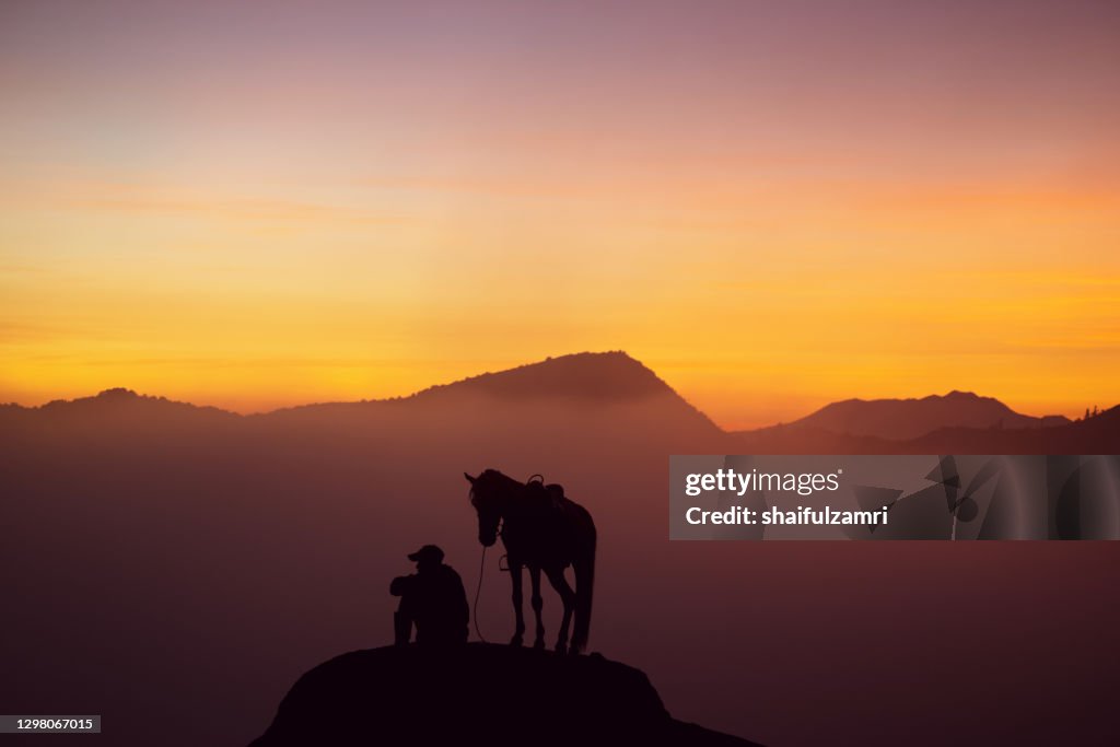 Silhouette of unidentified local people or Bromo Horseman at mountainside of Mount Bromo.