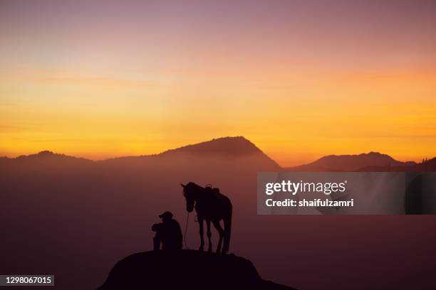 silhouette of unidentified local people or bromo horseman at mountainside of mount bromo. - bromo horse stock pictures, royalty-free photos & images