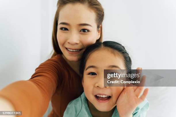 happy asian mother with cute girl waving towards camera - south korean girls stock pictures, royalty-free photos & images