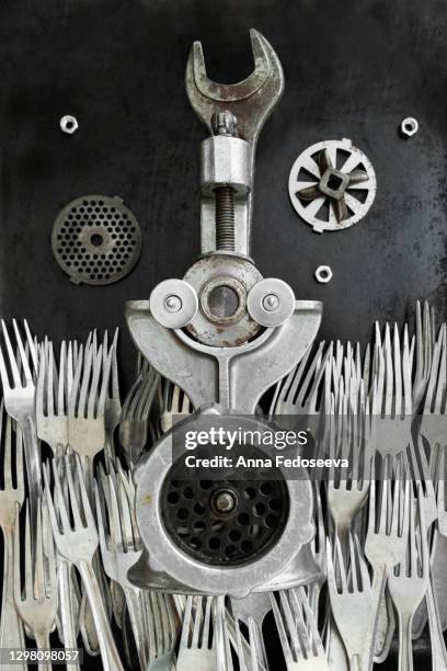 old meat grinder lies on an old wall in the middle of a sea of ​​forks. the design idea has transformed the subject of making it wonderful, fanastastic as from wonderland. a revived subject with eyes. - vleesmolen stockfoto's en -beelden