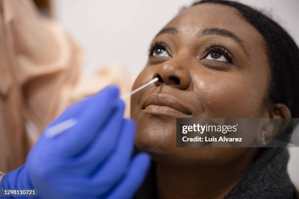 young woman undergoing a coronavirus test - coton tige photos et images de collection