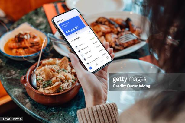 close-up shot of young woman managing bank account on smartphone at restaurant - dinner program stock pictures, royalty-free photos & images