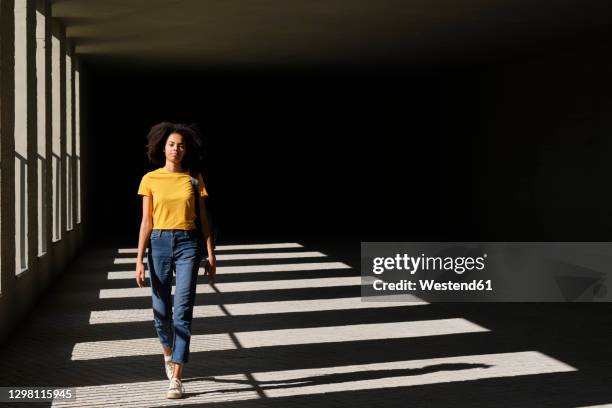 female student walking at university corridor - kontrastreich stock-fotos und bilder