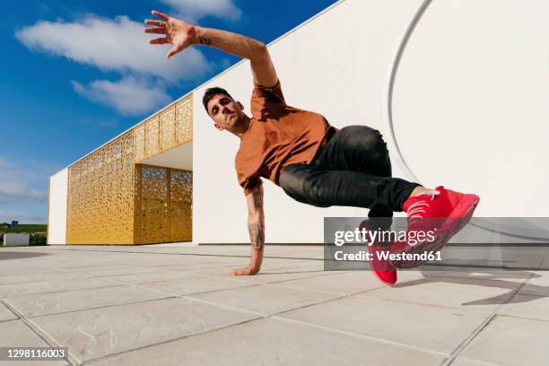 young man dancing on footpath during sunny day - street dance stock pictures, royalty-free photos & images