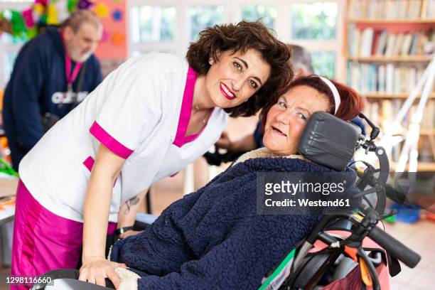 smiling female caregiver with disabled woman at rehabilitation center - promises rehab center bildbanksfoton och bilder