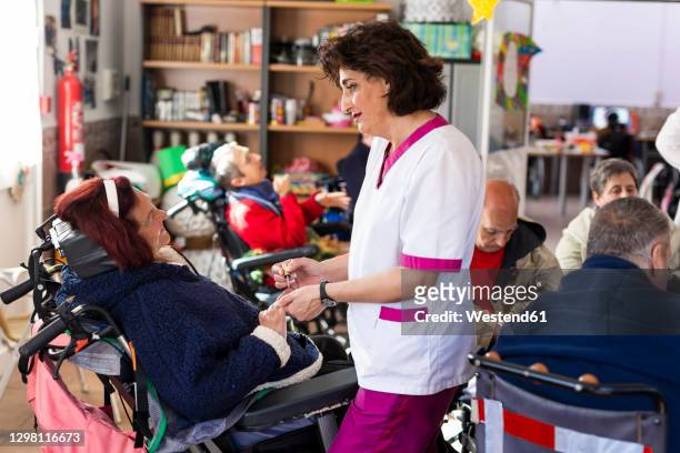 female caregiver applying nail polish to disabled woman at rehabilitation center - promises rehab center bildbanksfoton och bilder