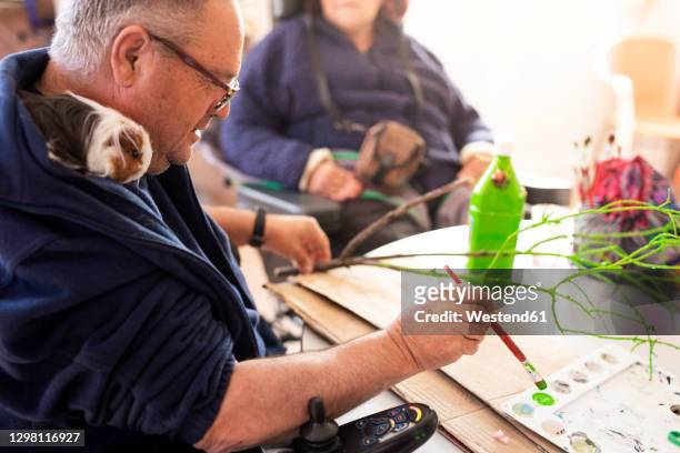 mature disabled man painting twig at rehabilitation center - promises rehab center bildbanksfoton och bilder
