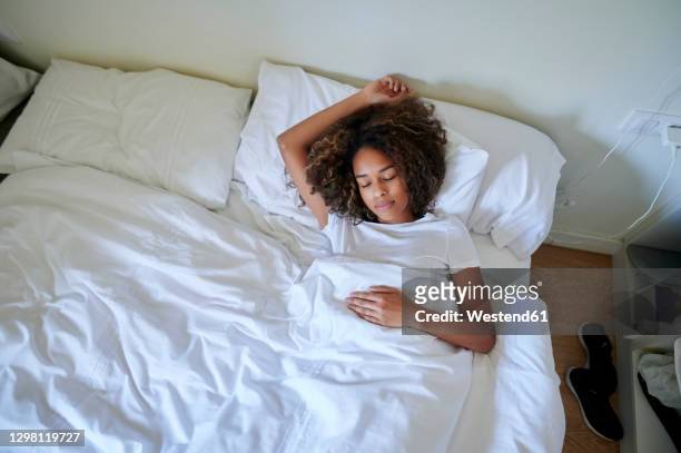 young woman sleeping on bed in bedroom at home - descansar imagens e fotografias de stock