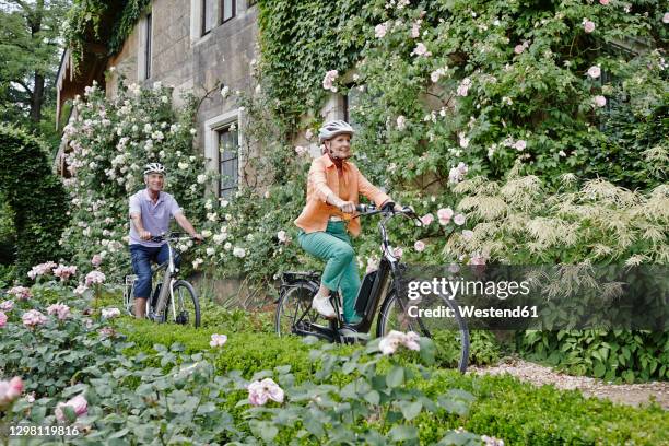 smiling couple cycling electric bicycle while exploring park at dresden, germany - city 70's stock pictures, royalty-free photos & images