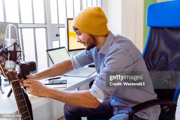 musician adjusting camera tripod while sitting at studio - make music day stock pictures, royalty-free photos & images