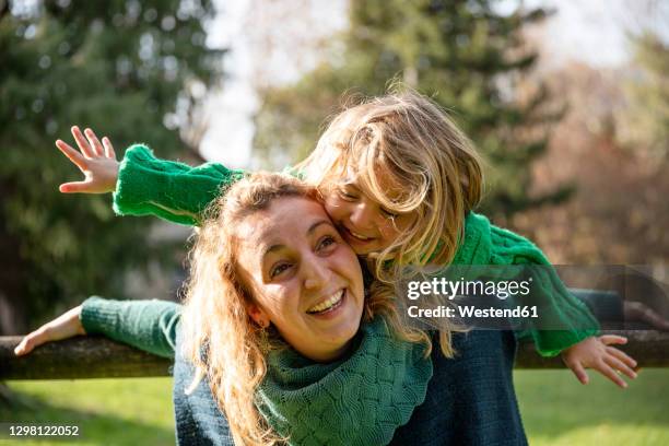 smiling mother piggybacking girl while standing at park - pretending to be a plane stock pictures, royalty-free photos & images