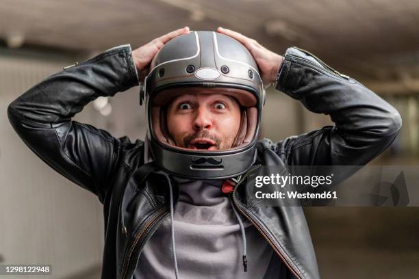 cheerful mature man wearing helmet while sitting in parking lot - crash helmet stock pictures, royalty-free photos & images