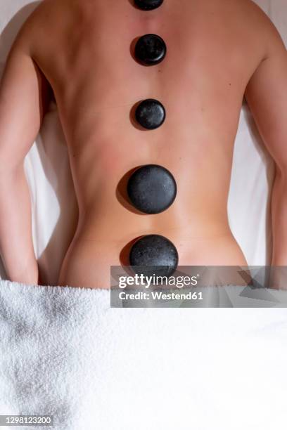 young woman lying on massage table during lastone therapy at health spa - マッサージ台 ストックフォトと画像