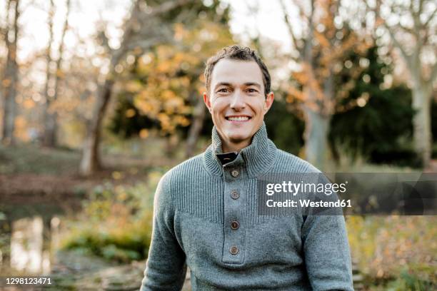 smiling handsome man sitting in public park - 35 39 jahre stock-fotos und bilder