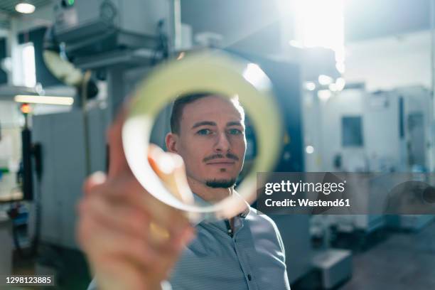 mid adult businessman seen through circular equipment in factory - mirar a través fotografías e imágenes de stock