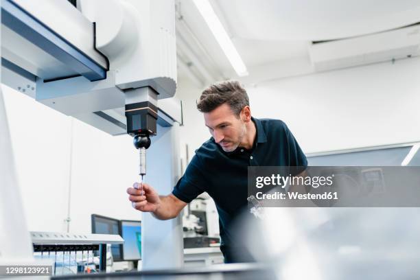 mature male technician fixing drill bit in machine at factory - drill bit stockfoto's en -beelden