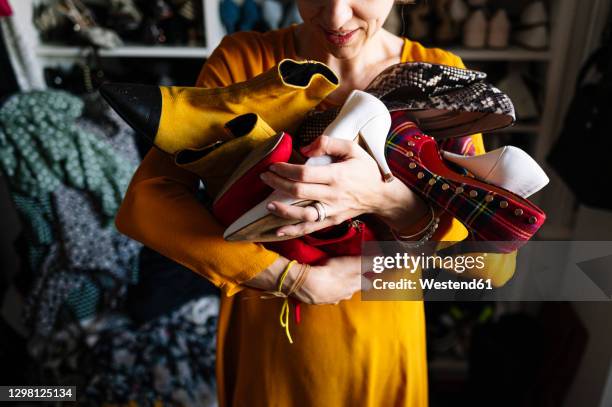 woman carrying variation of shoes in wardrobe at home - holding aloft stock-fotos und bilder