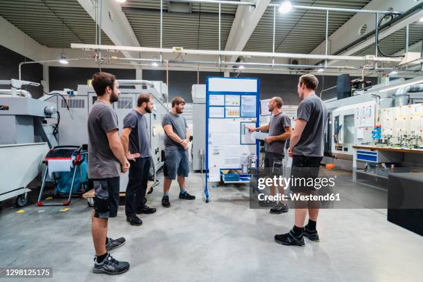 maintenance engineers planning over chart on whiteboard while standing in meeting at industry - leren korte broek stockfoto's en -beelden