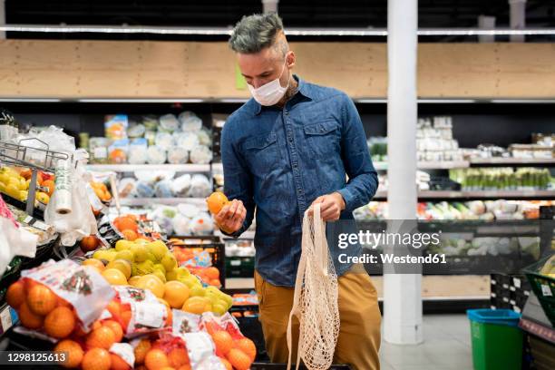 man wearing face mask buying fruits in supermarket - cloth mask 個照片及圖片檔