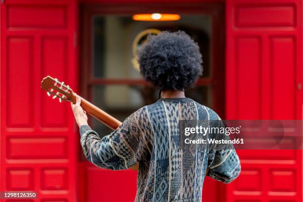 young man playing guitar while standing in front of building - male guitarist stock pictures, royalty-free photos & images