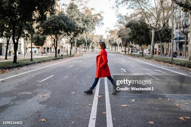 fashionable woman wearing winter jacket walking on road - seide photos et images de collection