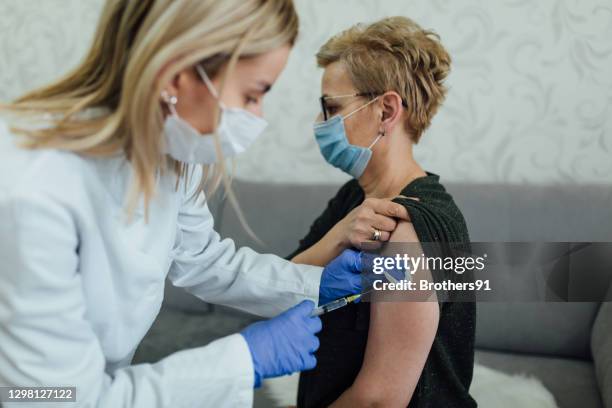 hogere kaukasische vrouw die een vaccin neemt - allergy doctor stockfoto's en -beelden