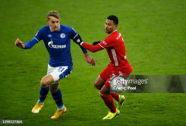 Timo Becker of FC Schalke 04 looks to break past Serge Gnabry during the Bundesliga match between FC Schalke 04 and FC Bayern Muenchen at...