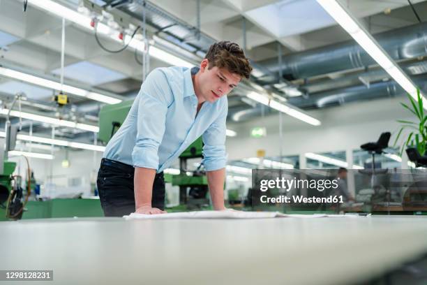 businessman examining blueprint at desk in industry - engineers brainstorming stock pictures, royalty-free photos & images