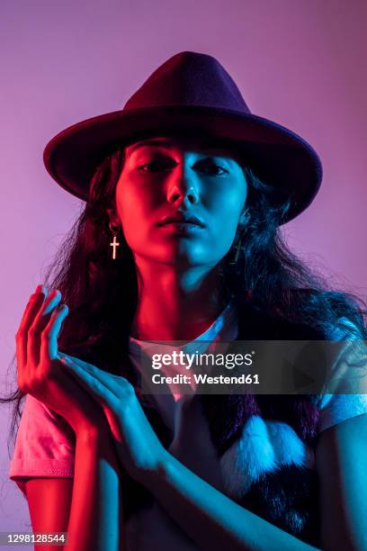 close portrait of teenage girl wearing hat against purple background - illuminated portrait stock pictures, royalty-free photos & images