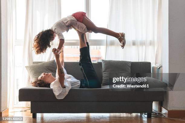 mother and daughter playing on sofa - lying on back girl on the sofa stock pictures, royalty-free photos & images