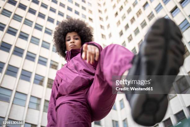 fashionable young woman with cool attitude gesturing against building exterior - vista de ángulo bajo fotografías e imágenes de stock