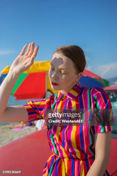 woman shielding eyes while sitting on car at beach - car sunshade stock pictures, royalty-free photos & images