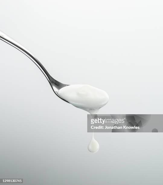 yogurt dripping off spoon - jogurt textur stock-fotos und bilder