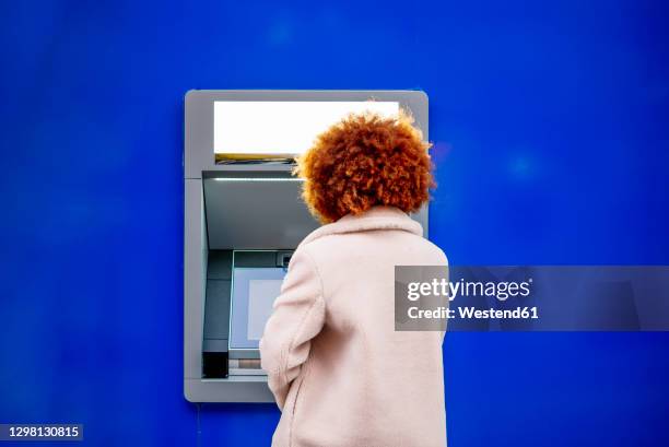 mid adult woman with afro hair using kiosk in city - banco de españa fotografías e imágenes de stock