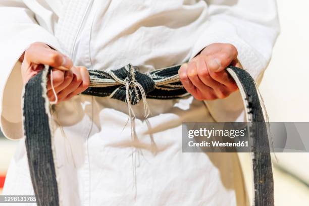 close-up of mature man tying black belt on waist in club - matériel de sport photos et images de collection