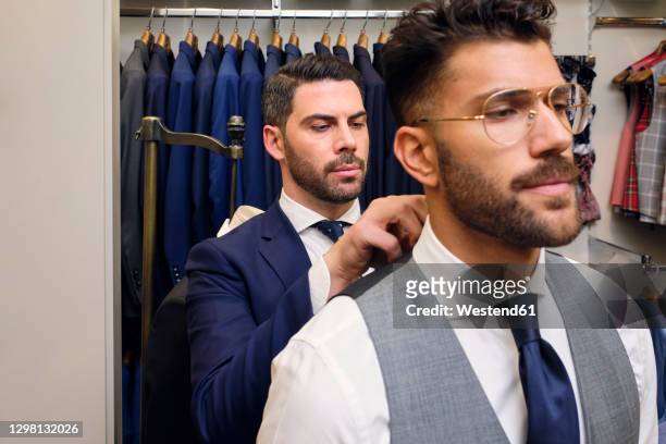 tailor in his menswear store adjusting customers shirt collar - kragen stock-fotos und bilder