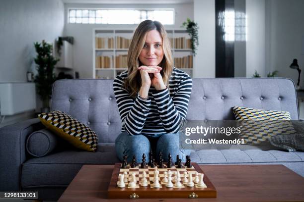 portrait of woman sitting on sofa in front of chess board - playing chess stock-fotos und bilder
