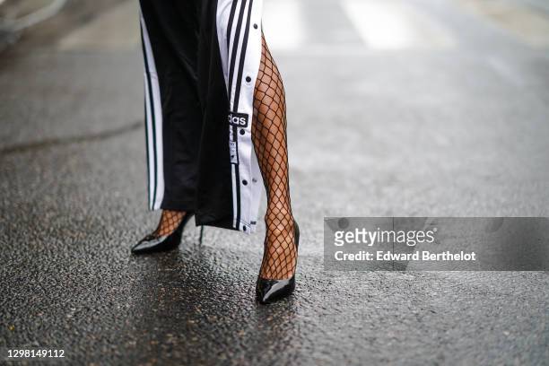 Emilie Joseph wears black and white striped Adidas flared jogger sport pants, fishnet tights from Calzedonia, black high heeled pointy shiny shoes...