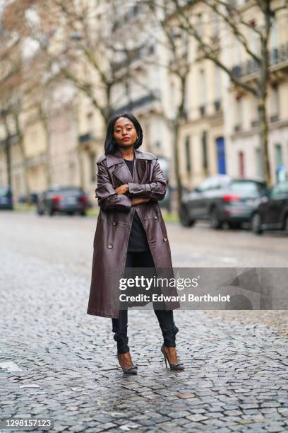 Carrole Sagba aka Linaose wears a brown long leather double breasted trench vintage coat, a black top, black pants from H&M, bejeweled high heeled...