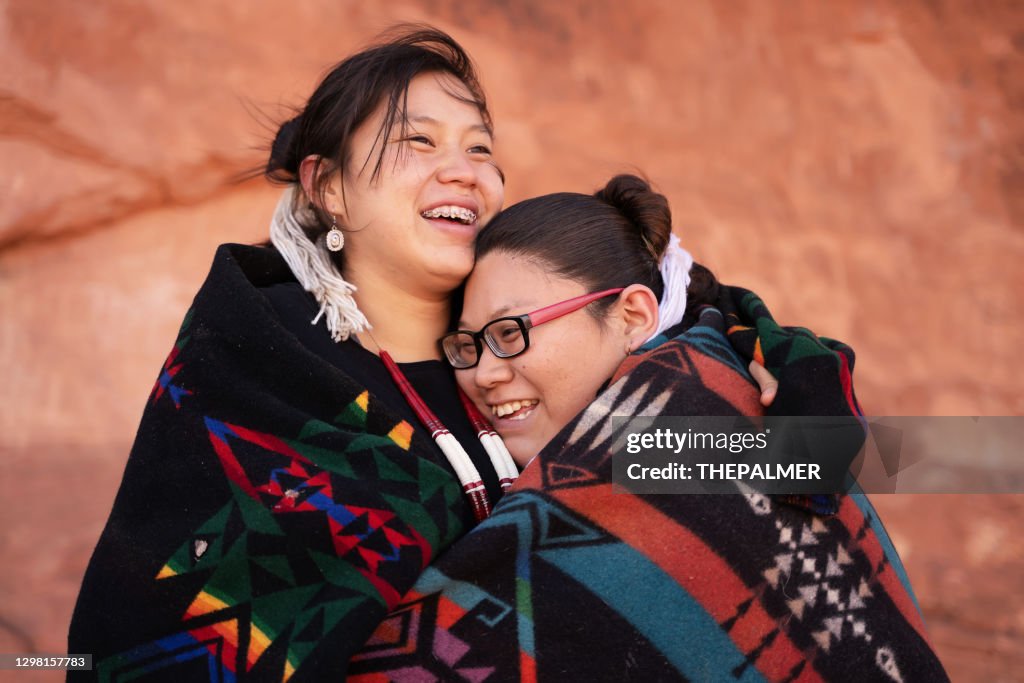 Cheerful navajo sisters hugging