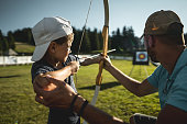 Little boy learning how to use bow with instructor