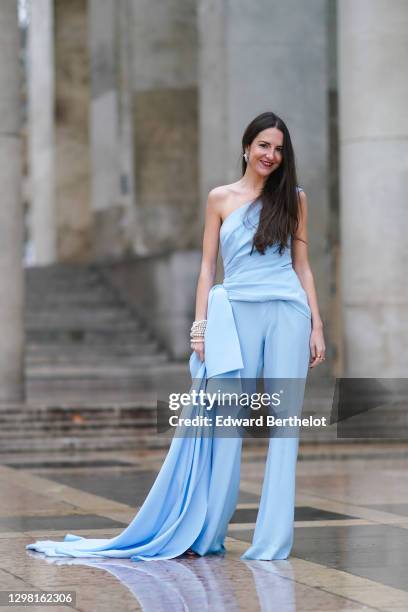 Alba Garavito Torre wears a one-shoulder / off-shoulder flowing top / dress and pale blue flared pants from Tony Ward, Jimmy Choo golden sandals,...