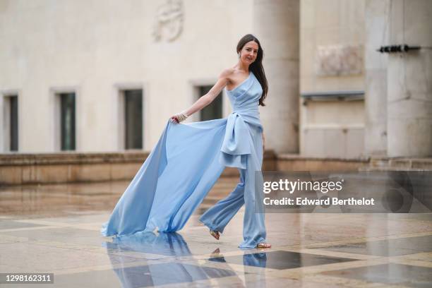 Alba Garavito Torre wears a one-shoulder / off-shoulder flowing top / dress and pale blue flared pants from Tony Ward, Jimmy Choo golden sandals,...