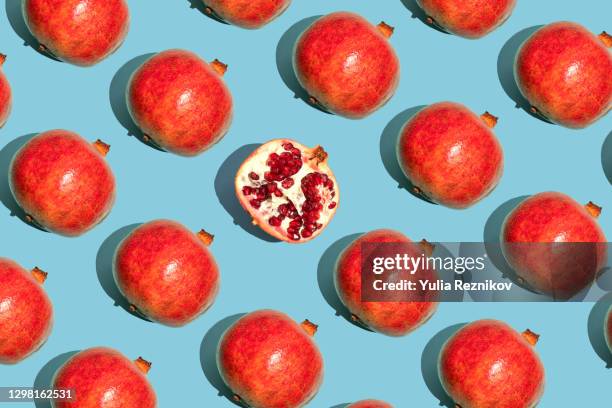 repeated pomegranates and one half sliced pomegranate on the blue background - pomegranate stock pictures, royalty-free photos & images