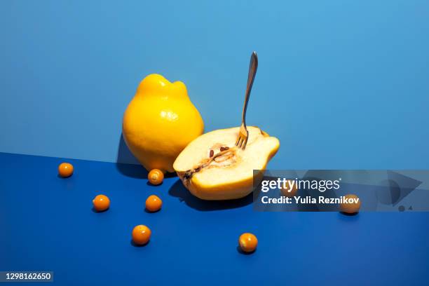 yellow quince and ground cherries (physalis) with fork on the blue background - kweepeer stockfoto's en -beelden