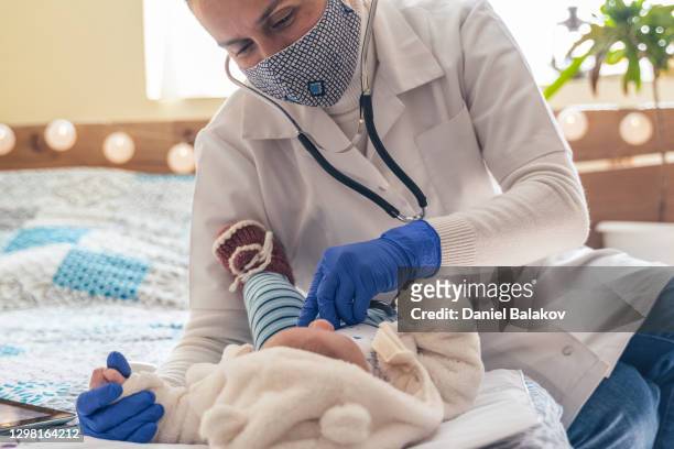 home caregiver. doctor's visit to a newborn baby at home during covid-19 pandemic. wearing protective face mask for illness prevention. - respiratory disease stock pictures, royalty-free photos & images