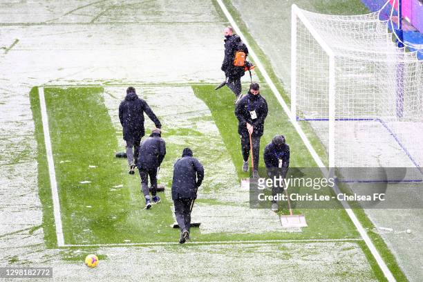 The Groundsmen clear snow off the pitch during The Emirates FA Cup Fourth Round match between Chelsea and Luton Town at Stamford Bridge on January...