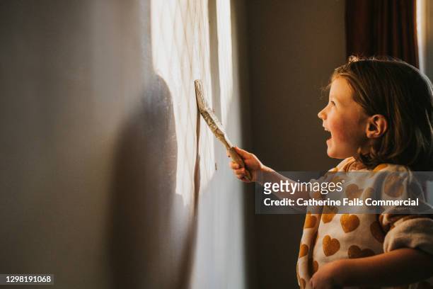 joyful child painting a wall with neutral white paint - children room wall stock pictures, royalty-free photos & images