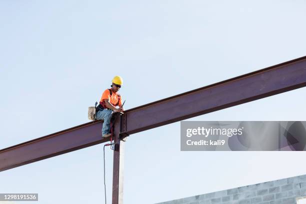 hispanischer eisenarbeiter arbeitet an einem stahlträger - dachbalken stock-fotos und bilder